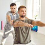 Sportmediziner betreut einen Patienten bei einer Reha-Übung